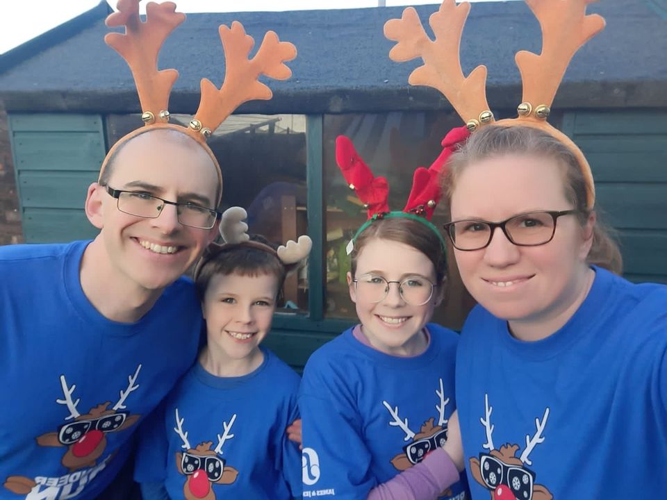 Two adults and two children smiling wearing blue reindeer t-shirts advertising the Noah's Ark Reindeer Run 2022